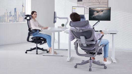 Two people working at desks in ergonomic chairs in a modern office setting.