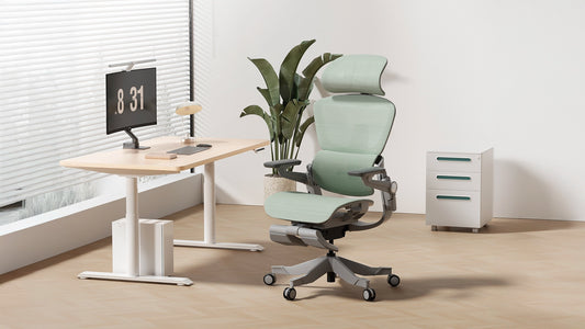 Minimalist home office featuring a green H1 Pro ergonomic chair, S1 standing desk, and greenery accents.