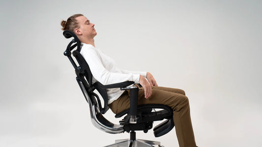 Man reclining in an ergonomic chair with headrest and lumbar support for comfort.