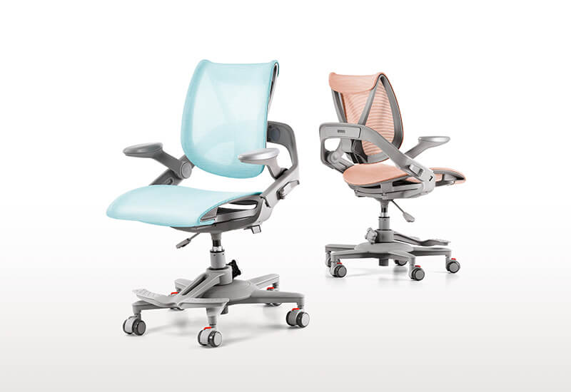 Blue and pink Hinomi Zee ergonomic children’s chairs placed side by side, showcasing their modern design and adjustable features.